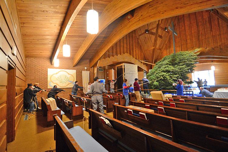 Everyone helps to lift the tree into position while carefully avoiding ceiling fixtures.  A custom-built wood structure protects the pipe organ.