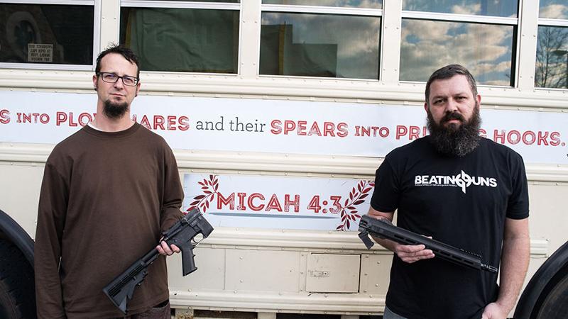 Shane Claiborne (left) and Michael Martin hold up an AK-47 they chopped in half.