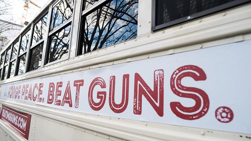 "Forge peace. Beat Guns." is emblazoned on the side of the tour bus.