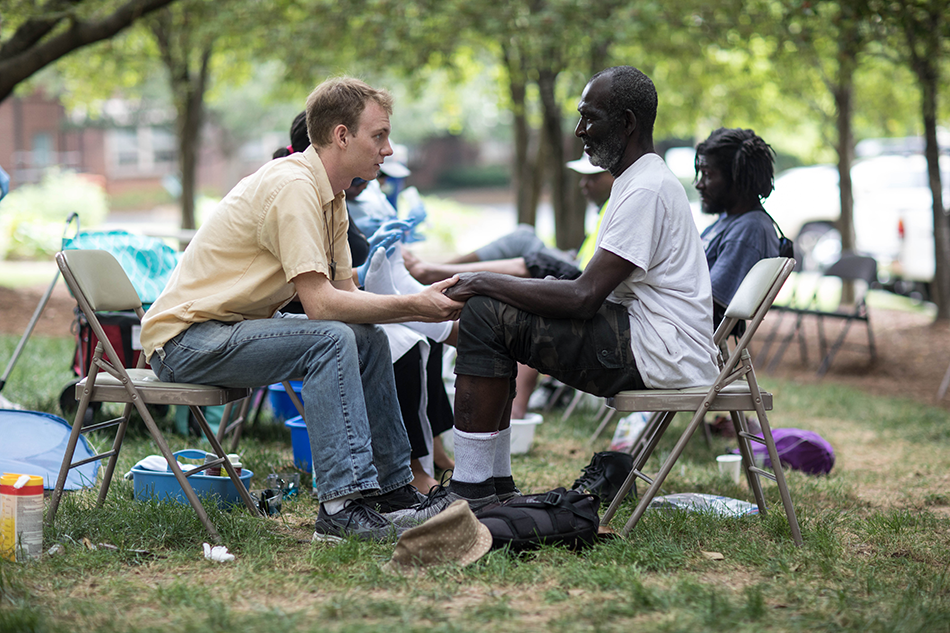 Windsor Jones washes Country's feet at the weekly Common Soles non-medical foot clinic.