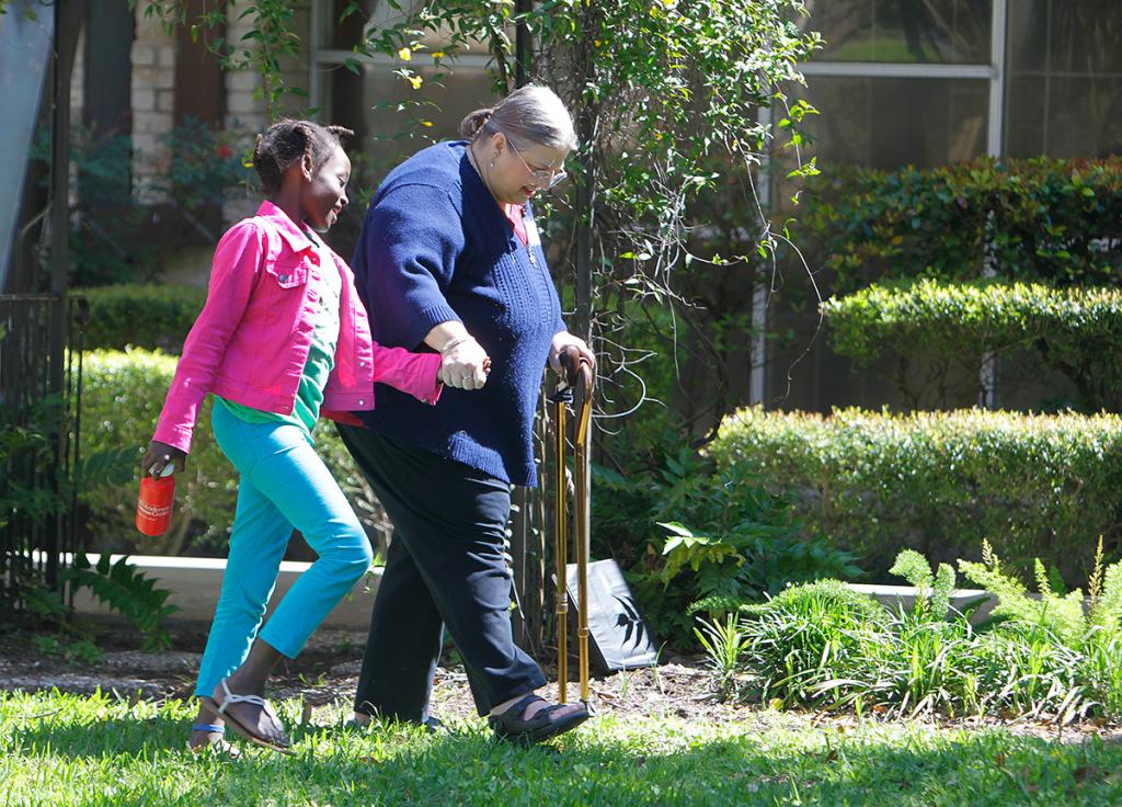 Olivia Nyirarukundo holds hands with Linda Tollefson after services at Westbury UMC.