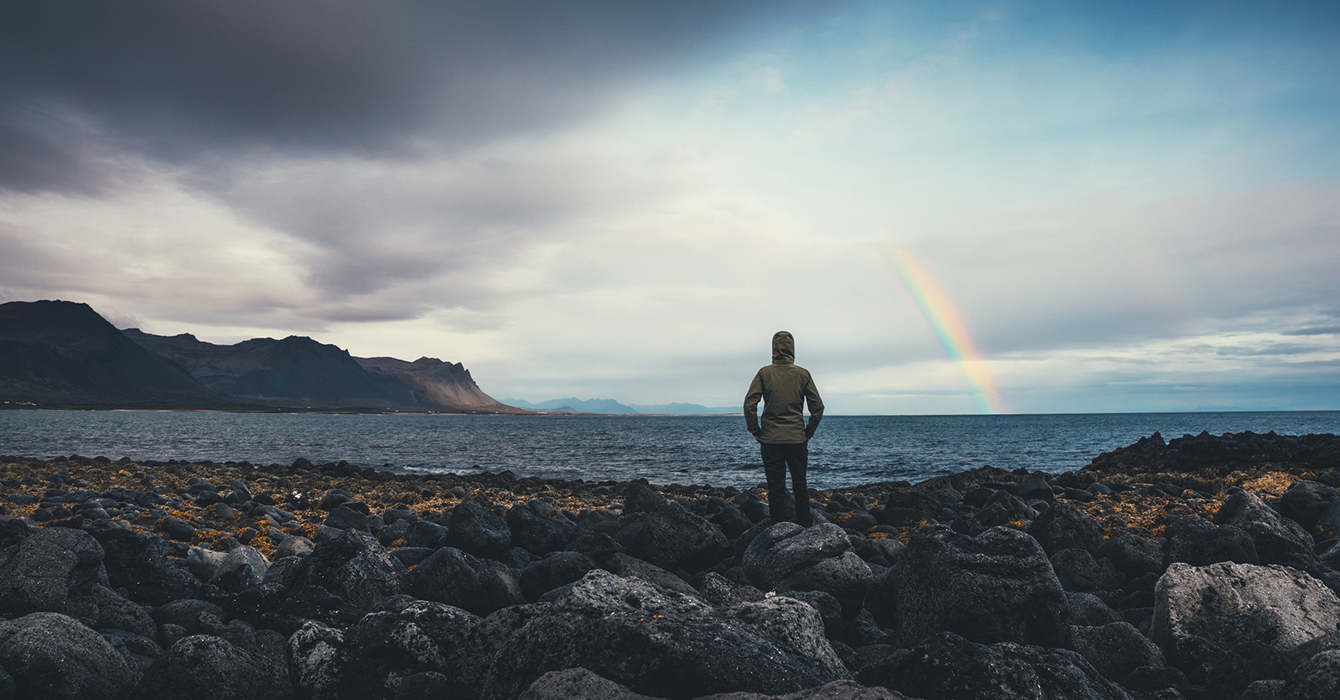 woman looking at rainbow in the distance