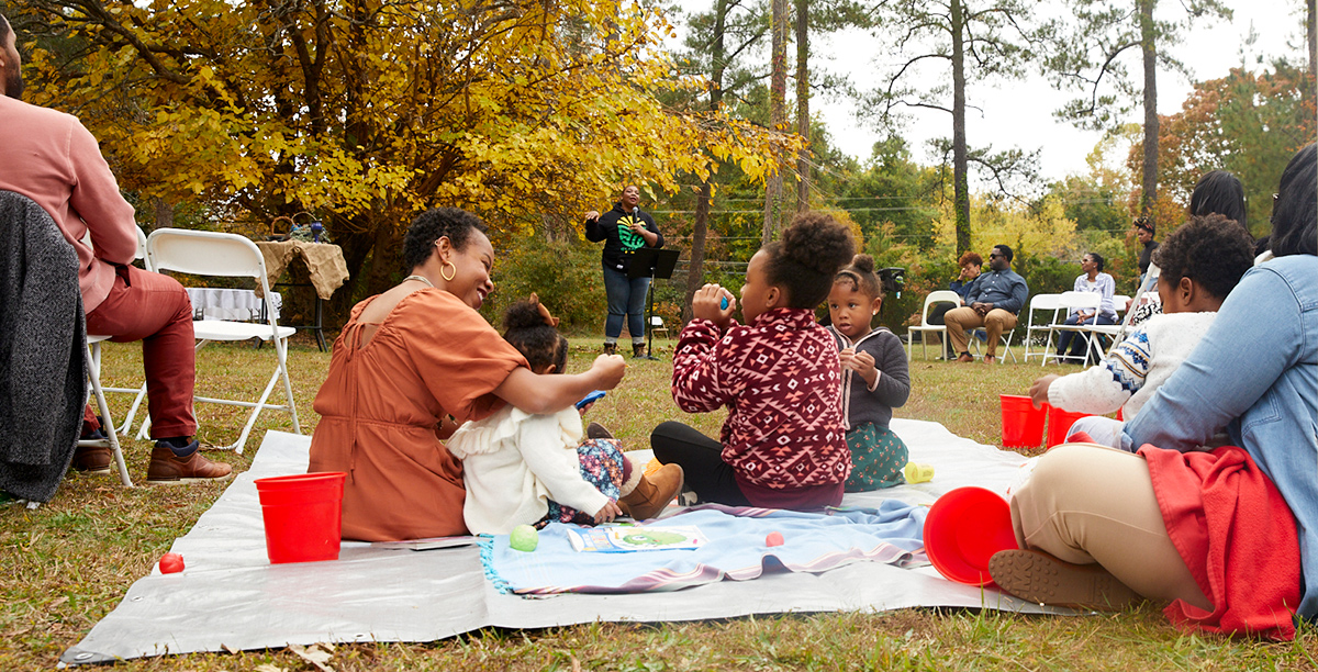 families sit on a blanket during service