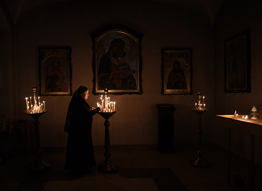 woman lights candles in a dark sanctuary