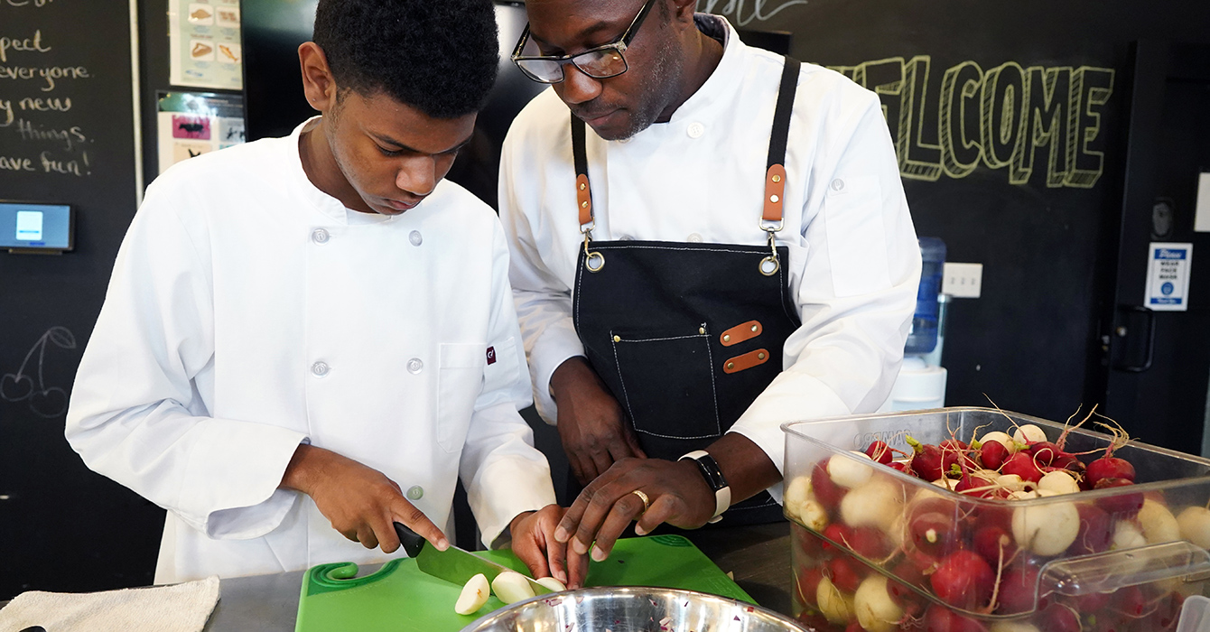 chef helps student with knife skills