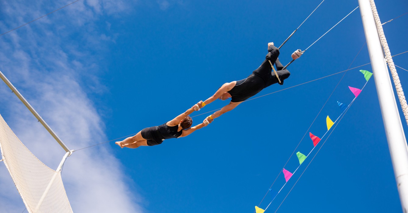 image of two trapeze artists swinging