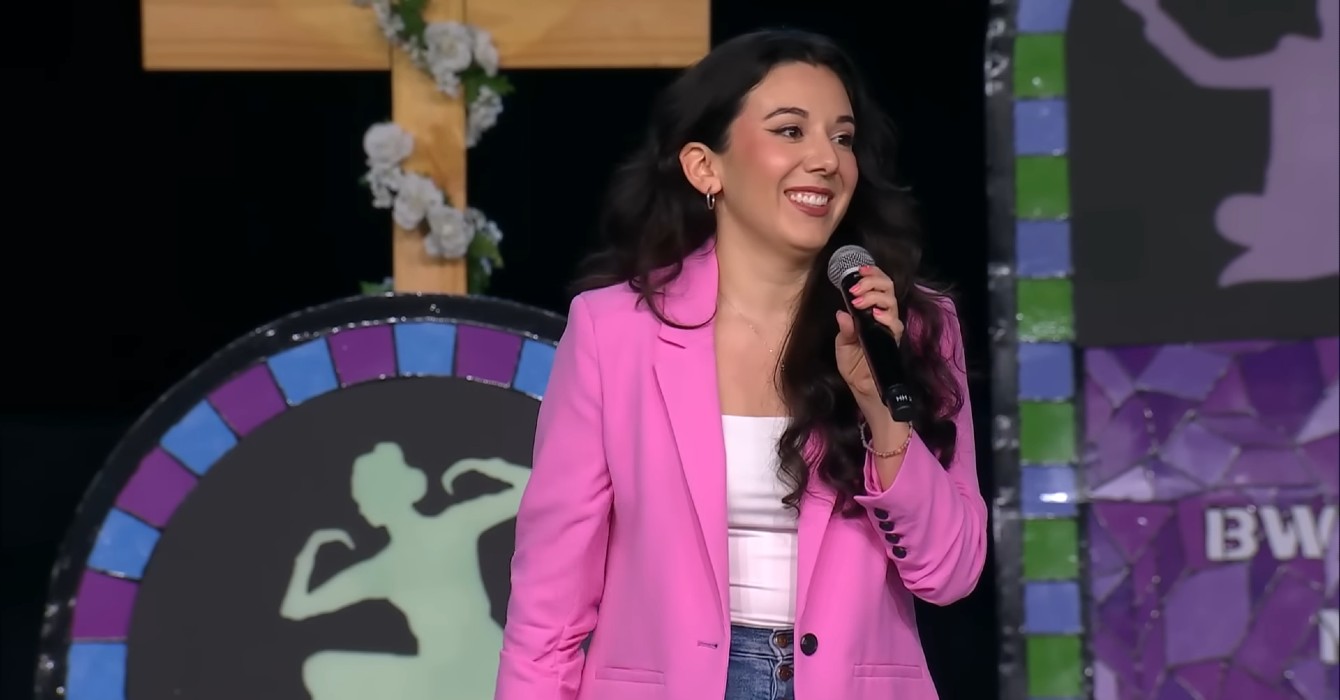 image of a woman in a pink blazer speaking on stage