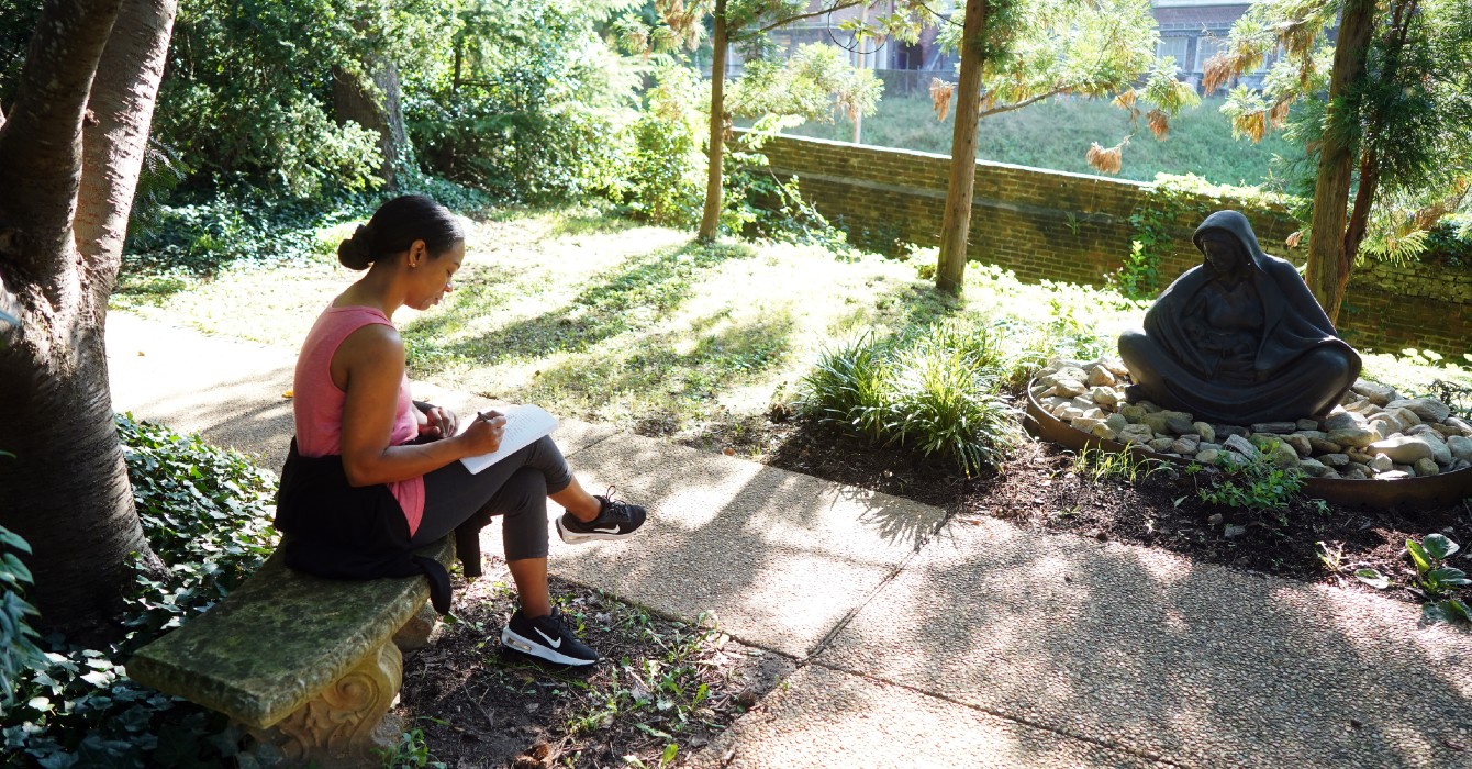 photo of a woman sitting in a garden and journaling