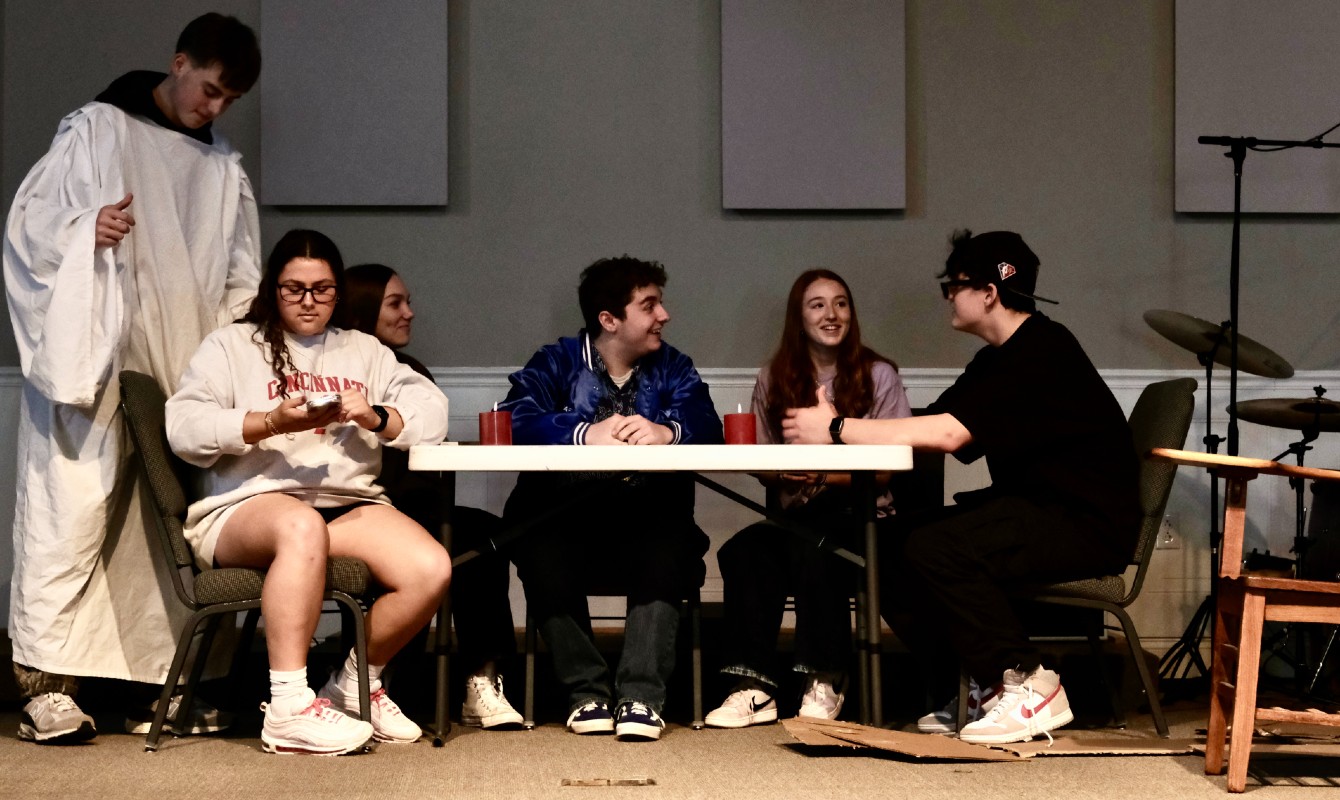 Photo of actors seated around a table
