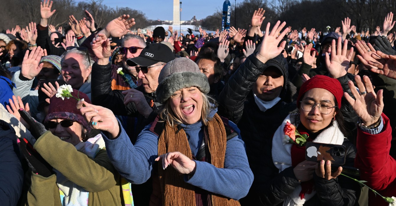 Photo of a woman singing and holding a flower in a crowd