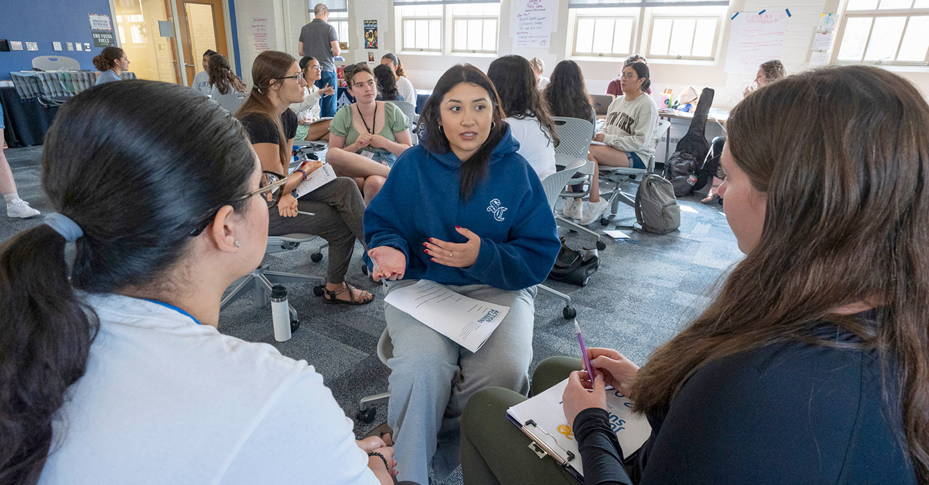 Young people sit together taking notes and talking