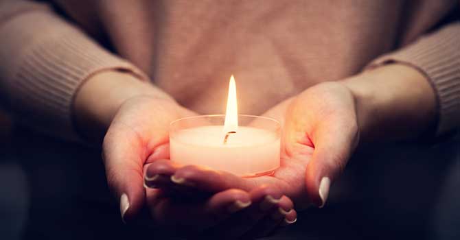 Woman's hands hold a lit candle