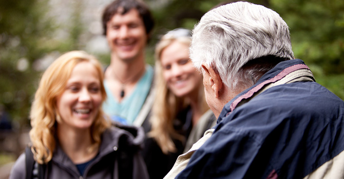 Elderly man talking to several young adults