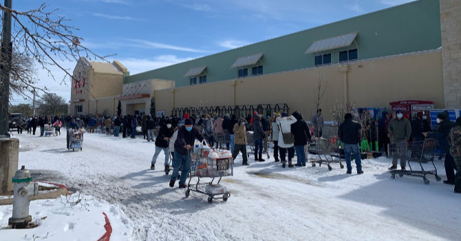Line of people in snow covered parking lot during Texas energy grid failure
