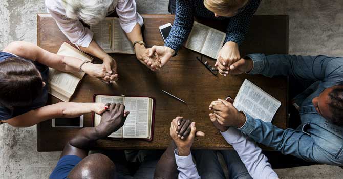 Multiracial group of people holding hands and praying