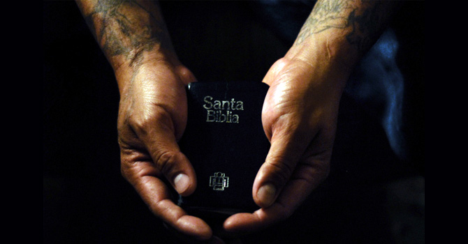 Tattooed hands hold a Santa Biblia (Holy Bible)