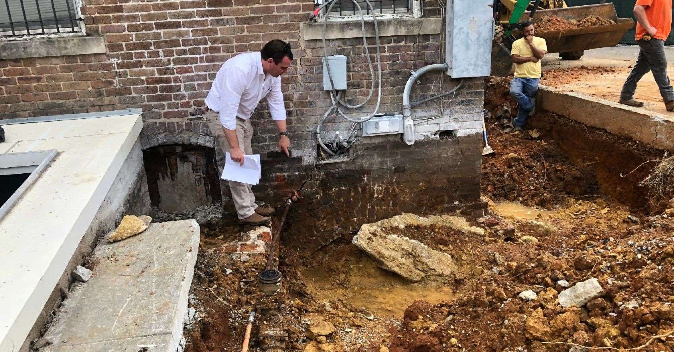 Image of a man inspecting the foundation of a building